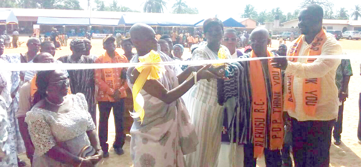 Mr Lawrence Awuye (in smock) chairman of the event, being assisted to cut the tape to inaugurate the six-unit classroom block. With him are Mr Freeman Gobah (right) and other dignitaries.